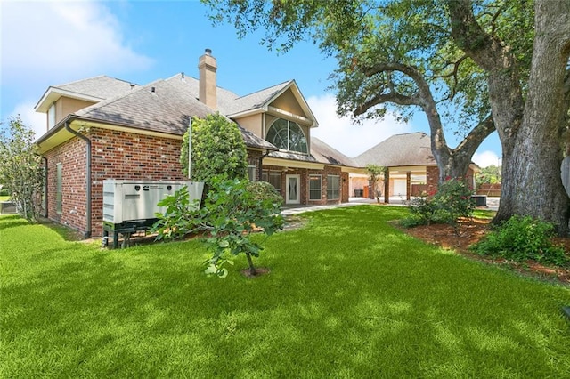 142 Colony Rd, Belle Chasse, LA 70037 - back of property with brick siding, a chimney, a yard, and roof with shingles