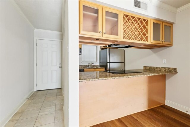 3805 Houma Blvd Unit B221, Metairie, LA 70006 - kitchen with freestanding refrigerator, ornamental molding, stone countertops, glass insert cabinets, and a peninsula