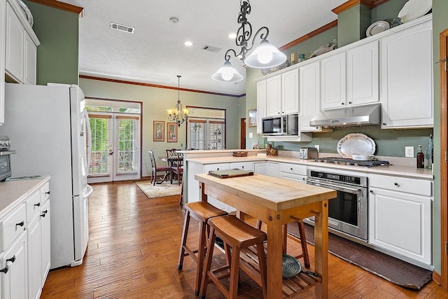 126 Gemstone Dr, Franklinton, LA 70438 - kitchen with appliances with stainless steel finishes, under cabinet range hood, a chandelier, crown molding, and light countertops