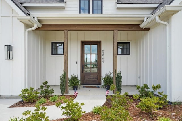 52554 Shore Dr, Franklinton, LA 70438 - view of exterior entry with covered porch, roof with shingles, and board and batten siding