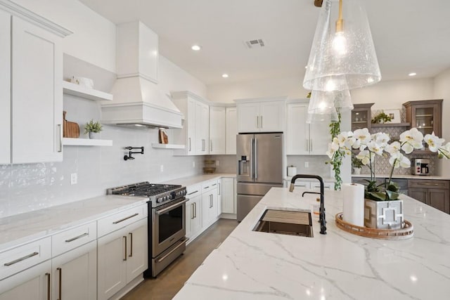 52554 Shore Dr, Franklinton, LA 70438 - kitchen featuring stainless steel appliances, open shelves, white cabinets, premium range hood, and decorative backsplash