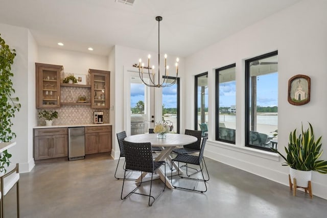 52554 Shore Dr, Franklinton, LA 70438 - dining room with concrete flooring, a chandelier, recessed lighting, and a water view