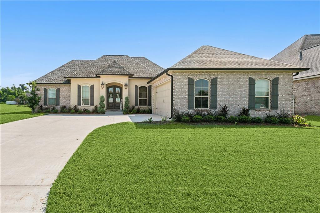 356 S Pass Dr, La Place, LA 70068 - french provincial home with french doors, driveway, an attached garage, a front lawn, and a shingled roof