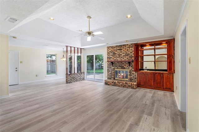 4013 Taft Park, Metairie, LA 70002 - unfurnished living room with a textured ceiling, a raised ceiling, a ceiling fan, light wood-type flooring, and a brick fireplace