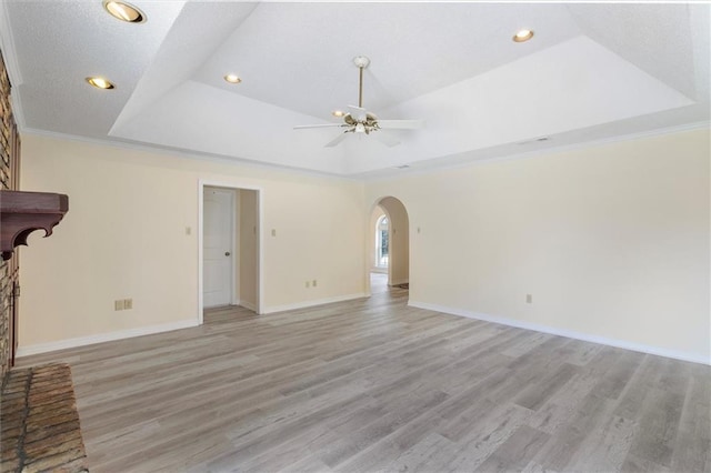 4013 Taft Park, Metairie, LA 70002 - unfurnished living room featuring a ceiling fan, arched walkways, light wood-style flooring, a tray ceiling, and crown molding