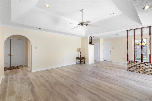 4013 Taft Park, Metairie, LA 70002 - unfurnished living room with arched walkways, a raised ceiling, light wood-type flooring, a ceiling fan, and a textured ceiling