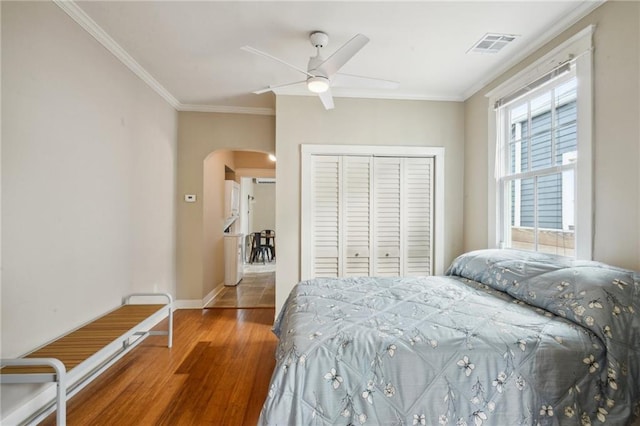 62426 9th St, New Orleans, LA 70115 - bedroom with arched walkways, wood finished floors, a closet, ornamental molding, and a ceiling fan
