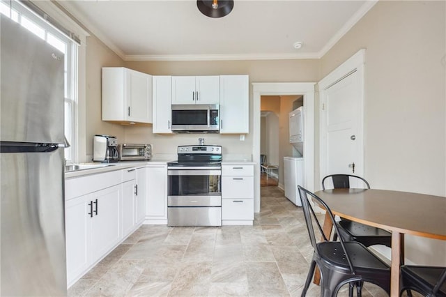 62426 9th St, New Orleans, LA 70115 - kitchen featuring stainless steel appliances, estacked washer and dryer, white cabinetry, light countertops, and crown molding