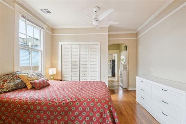 62426 9th St, New Orleans, LA 70115 - bedroom with arched walkways, light wood finished floors, crown molding, a closet, and a ceiling fan