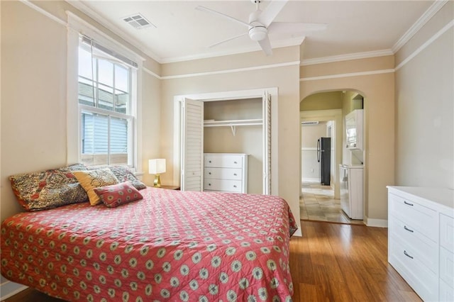 62426 9th St, New Orleans, LA 70115 - bedroom featuring arched walkways, wood finished floors, crown molding, freestanding refrigerator, and a closet