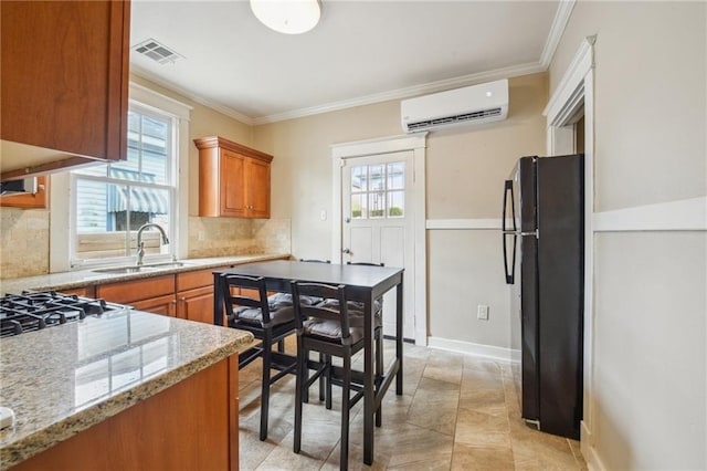 62426 9th St, New Orleans, LA 70115 - kitchen featuring a wall mounted AC, freestanding refrigerator, ornamental molding, backsplash, and plenty of natural light