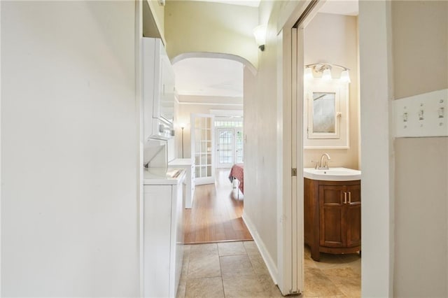 62426 9th St, New Orleans, LA 70115 - corridor featuring arched walkways, stacked washer and clothes dryer, and light tile patterned floors