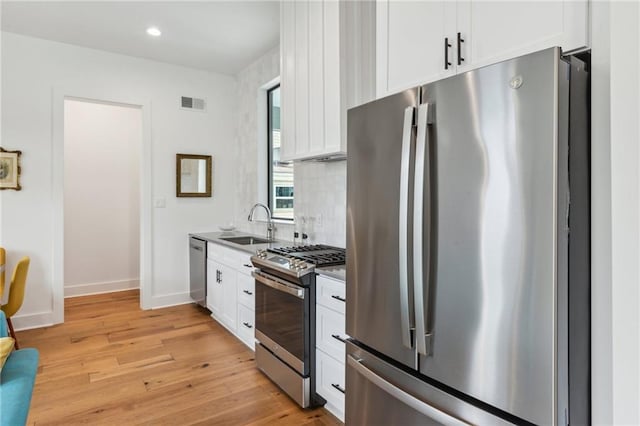 810 N Roman St, New Orleans, LA 70116 - kitchen with stainless steel appliances, light wood-style floors, white cabinetry, tasteful backsplash, and recessed lighting