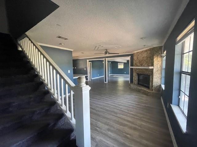 14151 W Hoffman Rd, Hammond, LA 70403 - unfurnished living room featuring a textured ceiling, a fireplace, dark wood finished floors, stairs, and ornamental molding