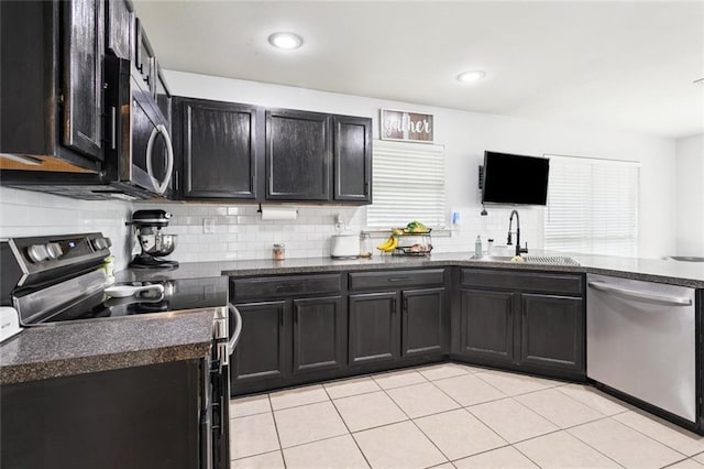 2311 Jay St, Slidell, LA 70460 - kitchen with appliances with stainless steel finishes, dark cabinetry, decorative backsplash, light tile patterned flooring, and dark stone countertops