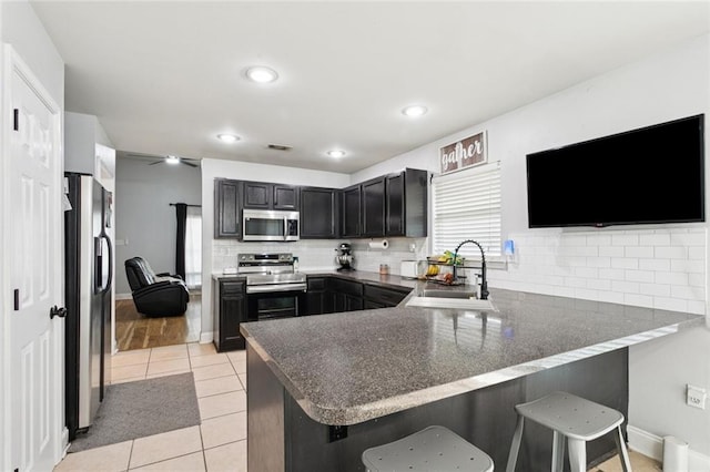 2311 Jay St, Slidell, LA 70460 - kitchen featuring appliances with stainless steel finishes, a peninsula, a kitchen breakfast bar, backsplash, and recessed lighting