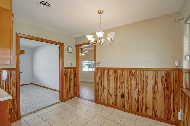 4213 Purdue Dr, Metairie, LA 70003 - unfurnished dining area featuring a chandelier, a ceiling fan, light tile patterned floors, light colored carpet, and a wainscoted wall