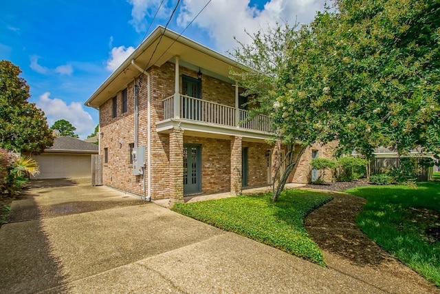 8808 Chretien Point Pl, River Ridge, LA 70123 - view of front of house featuring a balcony, brick siding, a front yard, and an outbuilding