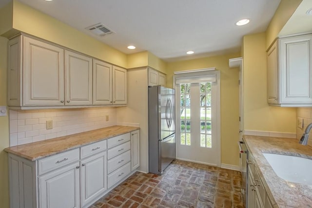 8808 Chretien Point Pl, River Ridge, LA 70123 - kitchen featuring freestanding refrigerator, brick flooring, backsplash, dishwashing machine, and recessed lighting