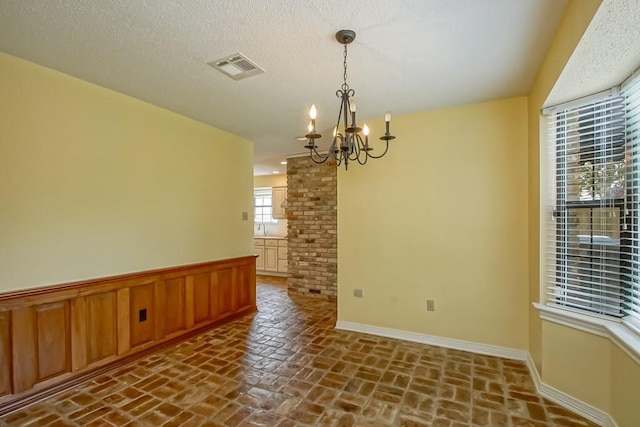8808 Chretien Point Pl, River Ridge, LA 70123 - spare room with a chandelier, brick floors, and a wainscoted wall