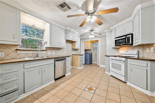 2142 Park Dr, Slidell, LA 70458 - kitchen featuring stainless steel appliances, washer / dryer, ceiling fan, decorative backsplash, and light tile patterned floors