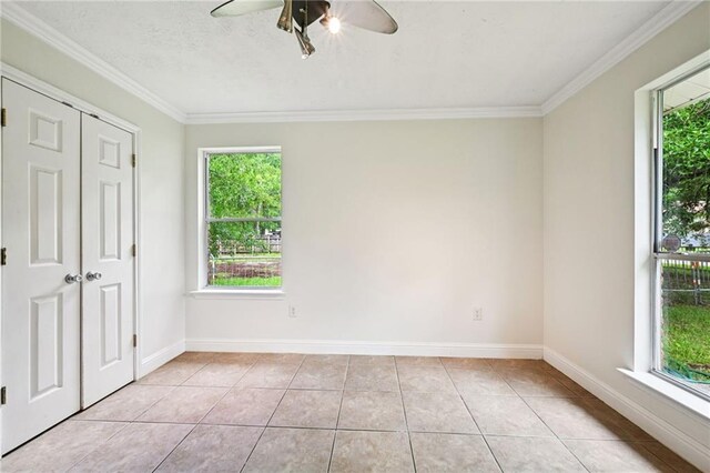 2142 Park Dr, Slidell, LA 70458 - unfurnished bedroom featuring multiple windows, ornamental molding, light tile patterned floors, ceiling fan, and a closet