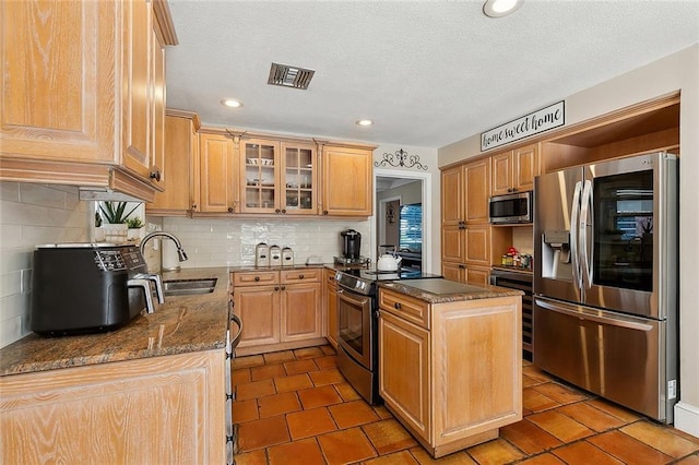 9408 Citrus Ln, River Ridge, LA 70123 - kitchen featuring appliances with stainless steel finishes, decorative backsplash, glass insert cabinets, dark stone countertops, and tile patterned floors