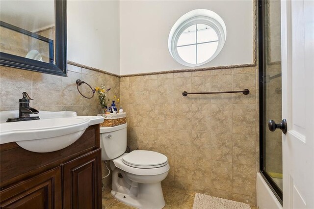 9408 Citrus Ln, River Ridge, LA 70123 - full bathroom featuring vanity, tile walls, wainscoting, enclosed tub / shower combo, and tile patterned flooring