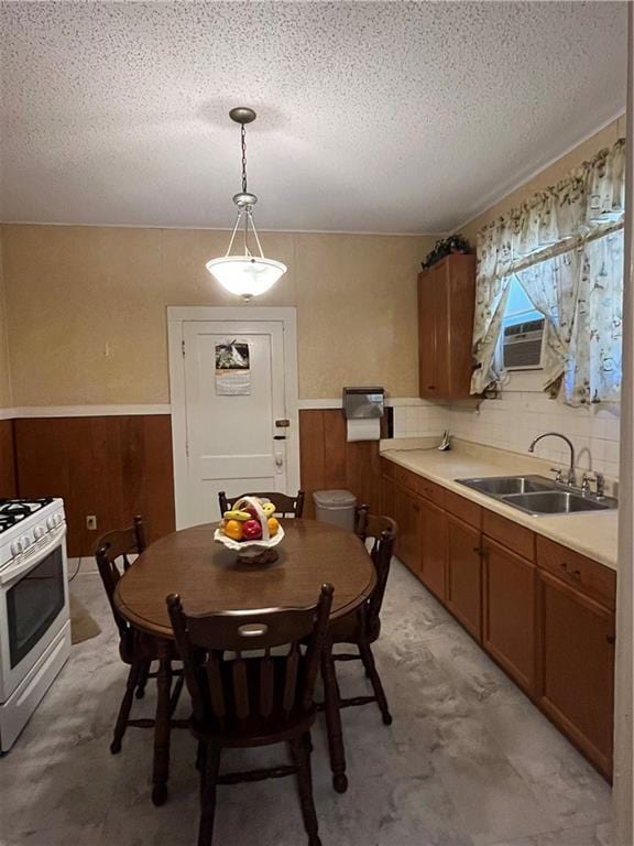 842426 Willow St, New Orleans, LA 70118 - kitchen featuring white range with gas stovetop, cooling unit, a textured ceiling, brown cabinets, and wainscoting