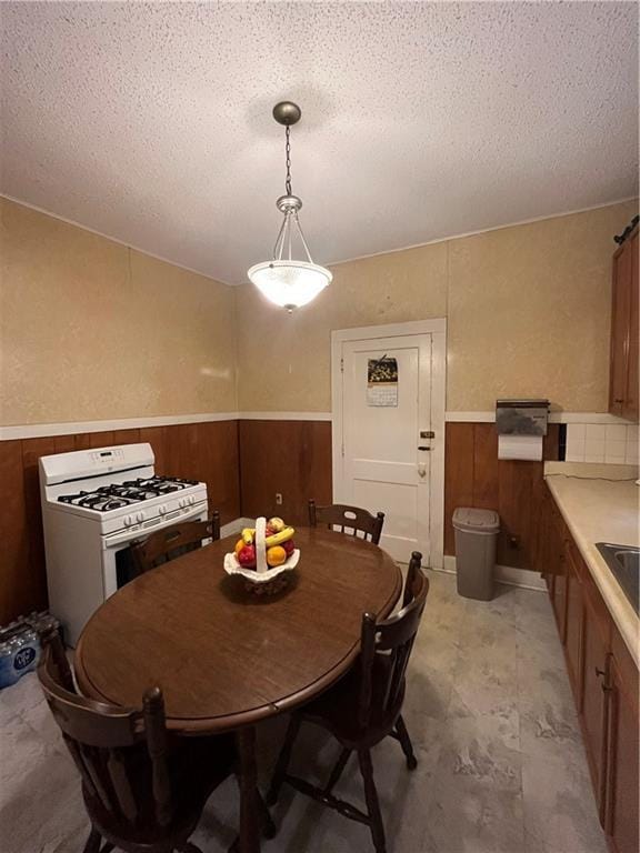 842426 Willow St, New Orleans, LA 70118 - dining space with wainscoting, a textured ceiling, and wooden walls