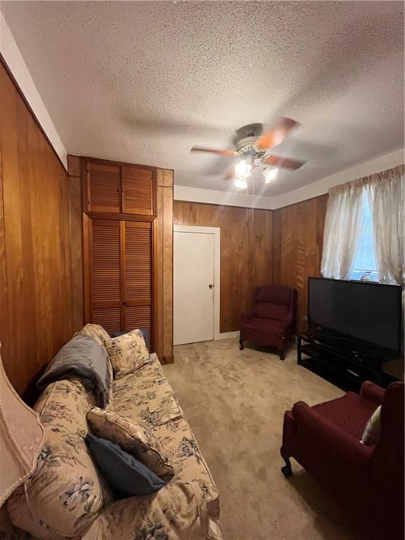 842426 Willow St, New Orleans, LA 70118 - living room featuring wood walls, a ceiling fan, a textured ceiling, and light colored carpet