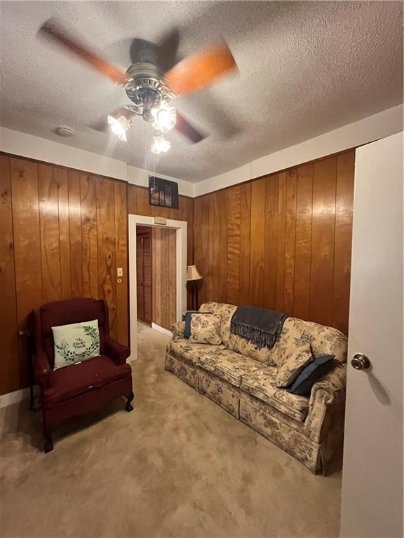 842426 Willow St, New Orleans, LA 70118 - living area featuring a ceiling fan, carpet, wood walls, and a textured ceiling