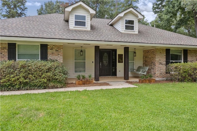426 Devon Dr, Mandeville, LA 70448 - view of front facade with a shingled roof, brick siding, a front yard, and a porch