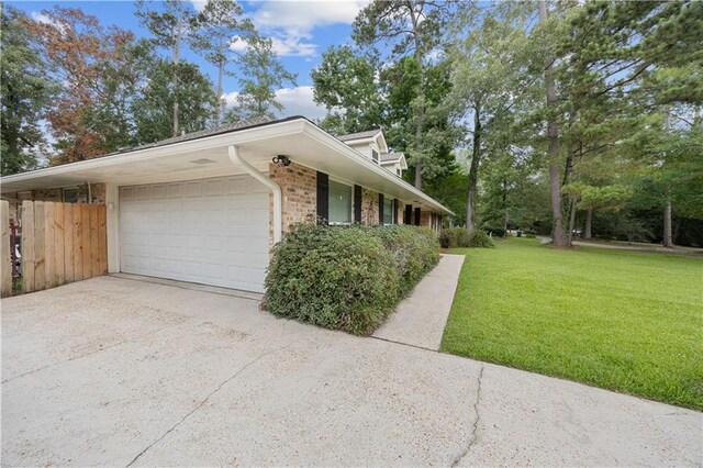 426 Devon Dr, Mandeville, LA 70448 - view of side of property featuring a lawn, an attached garage, concrete driveway, and brick siding