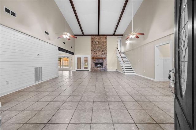 426 Devon Dr, Mandeville, LA 70448 - unfurnished living room featuring ceiling fan, high vaulted ceiling, beam ceiling, a large fireplace, and stairway