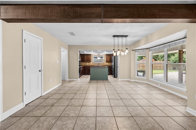 426 Devon Dr, Mandeville, LA 70448 - kitchen with freestanding refrigerator, light tile patterned floors, decorative backsplash, a center island, and open floor plan