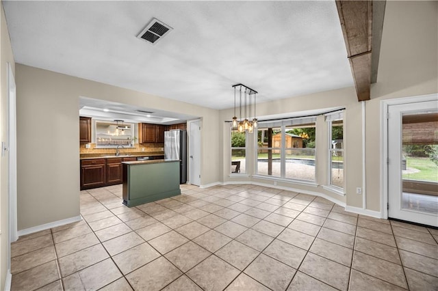 426 Devon Dr, Mandeville, LA 70448 - kitchen featuring freestanding refrigerator, light tile patterned flooring, backsplash, and a chandelier