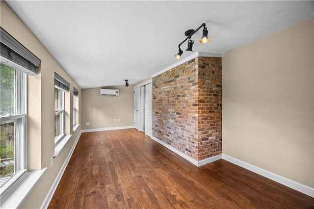 426 Devon Dr, Mandeville, LA 70448 - empty room with a wall mounted air conditioner, wood finished floors, vaulted ceiling, and track lighting