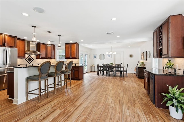 7320 General Haig St, New Orleans, LA 70124 - kitchen with wall chimney range hood, freestanding refrigerator, light wood-type flooring, a kitchen breakfast bar, and a kitchen island