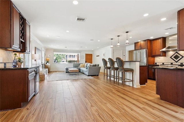 7320 General Haig St, New Orleans, LA 70124 - kitchen featuring wall chimney range hood, high quality fridge, a kitchen breakfast bar, open floor plan, and light wood-type flooring