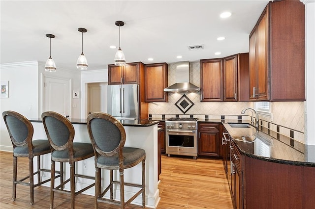 7320 General Haig St, New Orleans, LA 70124 - kitchen featuring appliances with stainless steel finishes, wall chimney range hood, a kitchen breakfast bar, light wood finished floors, and crown molding