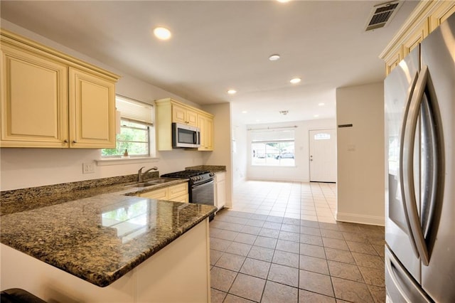 2808 Transcontinental Dr, Metairie, LA 70006 - kitchen featuring appliances with stainless steel finishes, cream cabinetry, healthy amount of natural light, light tile patterned flooring, and recessed lighting