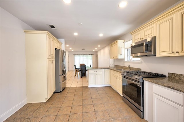 2808 Transcontinental Dr, Metairie, LA 70006 - kitchen featuring stainless steel appliances, cream cabinetry, a peninsula, recessed lighting, and dark stone counters