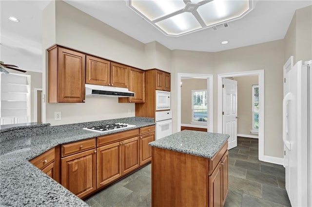 147 Jesuit Bend Dr, Belle Chasse, LA 70037 - kitchen featuring a ceiling fan, under cabinet range hood, white appliances, brown cabinets, and light stone countertops