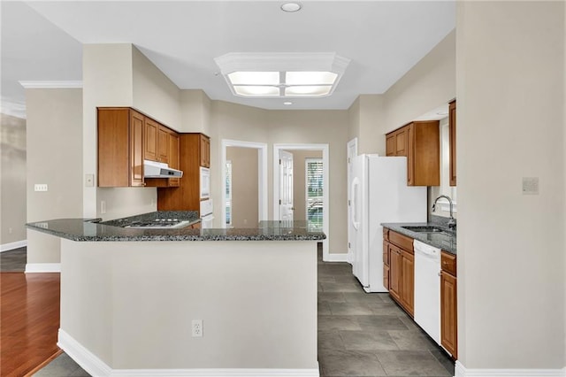 147 Jesuit Bend Dr, Belle Chasse, LA 70037 - kitchen with white appliances, dark stone countertops, a peninsula, brown cabinets, and recessed lighting