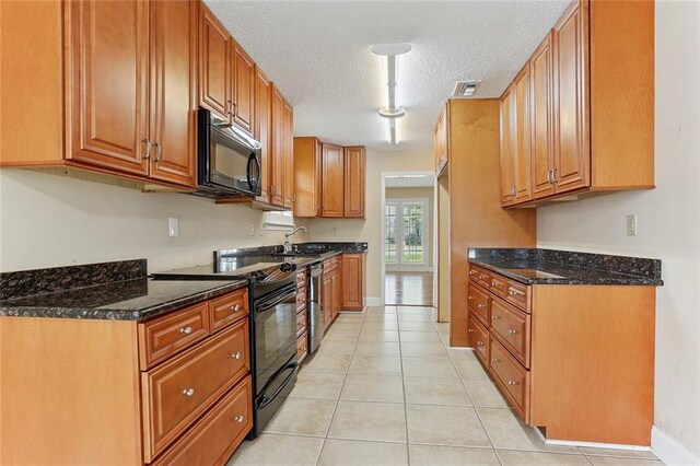 3632 N Hullen St, Metairie, LA 70002 - kitchen featuring black appliances, a textured ceiling, brown cabinets, dark stone countertops, and light tile patterned flooring