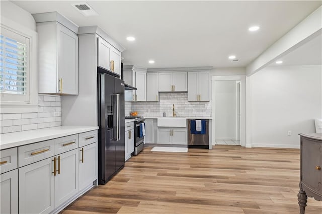 912 W 25th Ave, Covington, LA 70433 - kitchen with appliances with stainless steel finishes, backsplash, light countertops, light wood-style floors, and recessed lighting