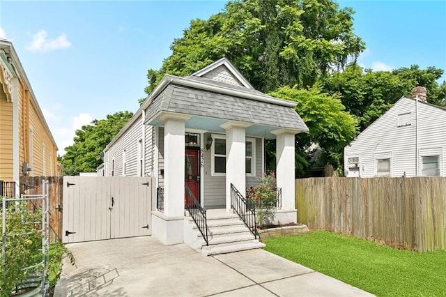 8426 Green St, New Orleans, LA 70118 - shotgun-style home featuring a gate, mansard roof, covered porch, and a shingled roof