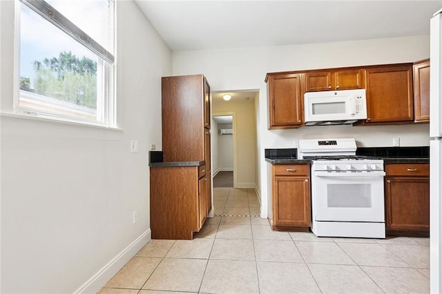 8426 Green St, New Orleans, LA 70118 - kitchen with white appliances, dark countertops, brown cabinetry, and light tile patterned floors