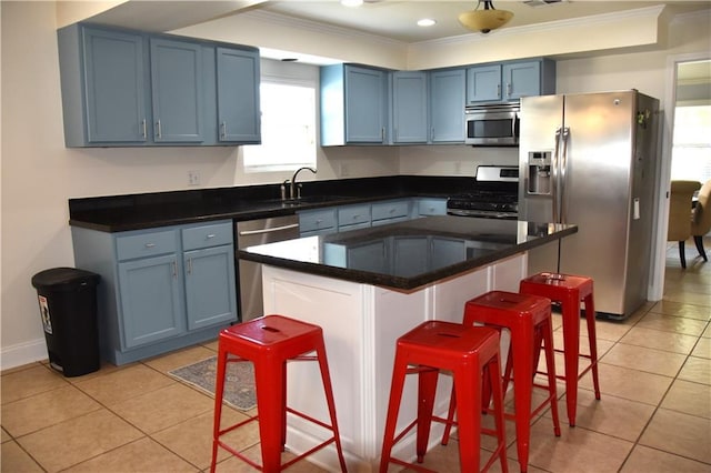 5501 Chatham Dr, New Orleans, LA 70122 - kitchen featuring stainless steel appliances, ornamental molding, blue cabinetry, a breakfast bar area, and light tile patterned floors
